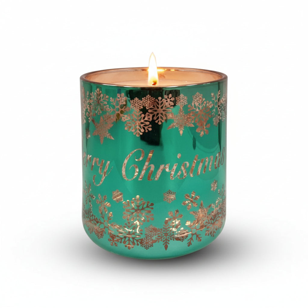 A green glass candle with rose gold accents and 'Merry Christmas' text, decorated with snowflake patterns.