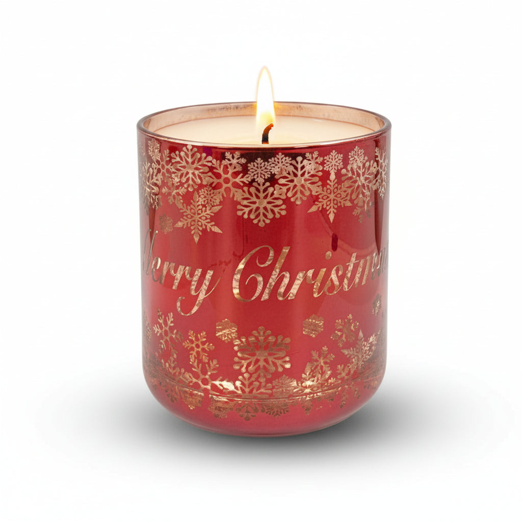 A red glass candle with rose gold accents and 'Merry Christmas' text design, presented in a clear glass jar with a decorative pattern.